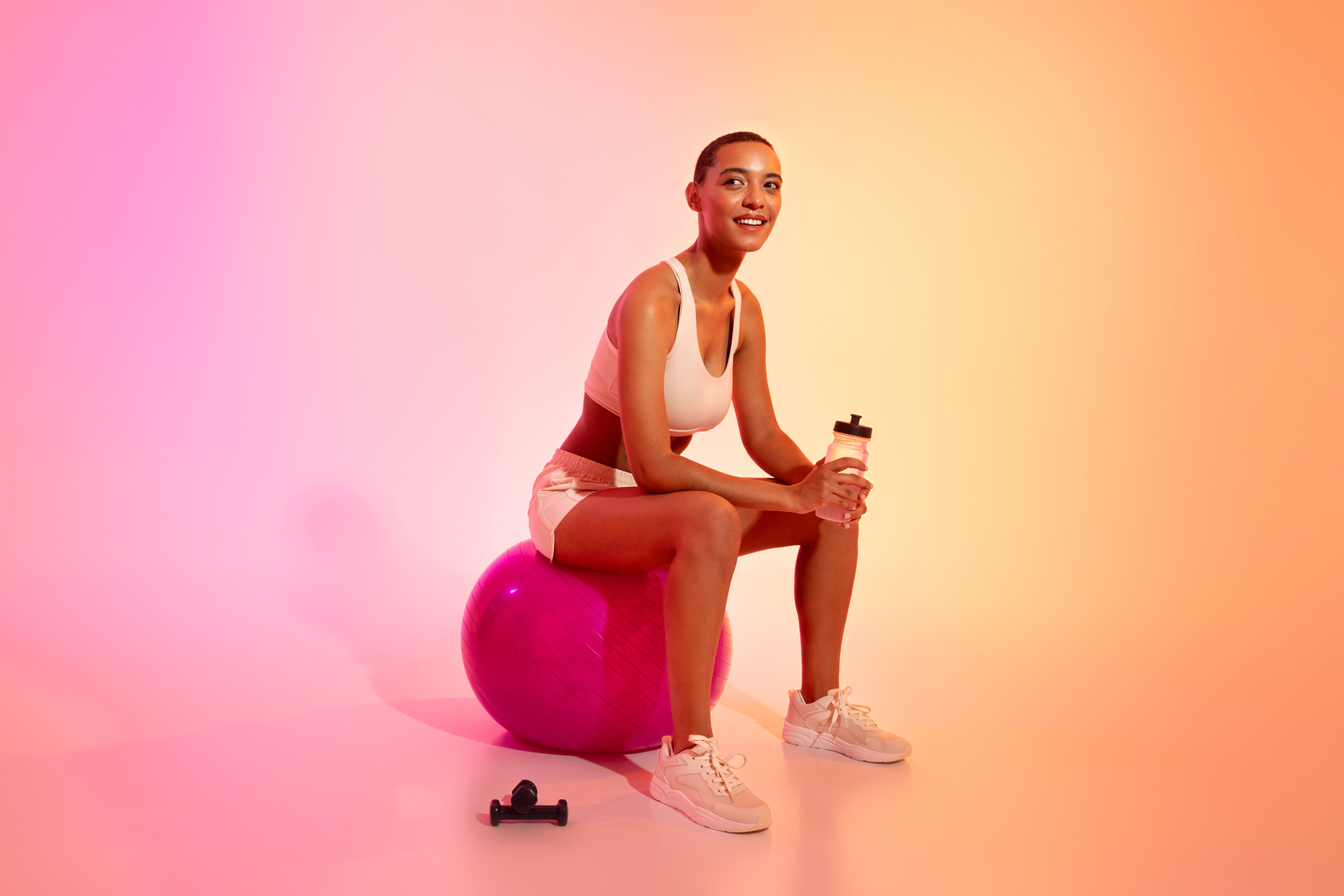 Smiling athlete with a drink bottle on a fitness ball — Daily Wellness Stack